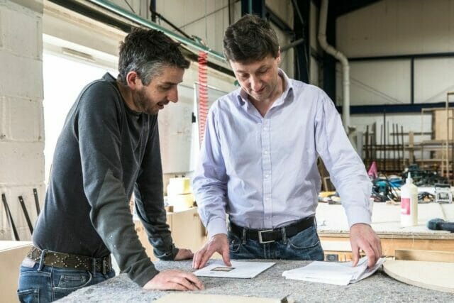 Design consultation between craftsmen at Higham Furniture, discussing materials and cabinetry details