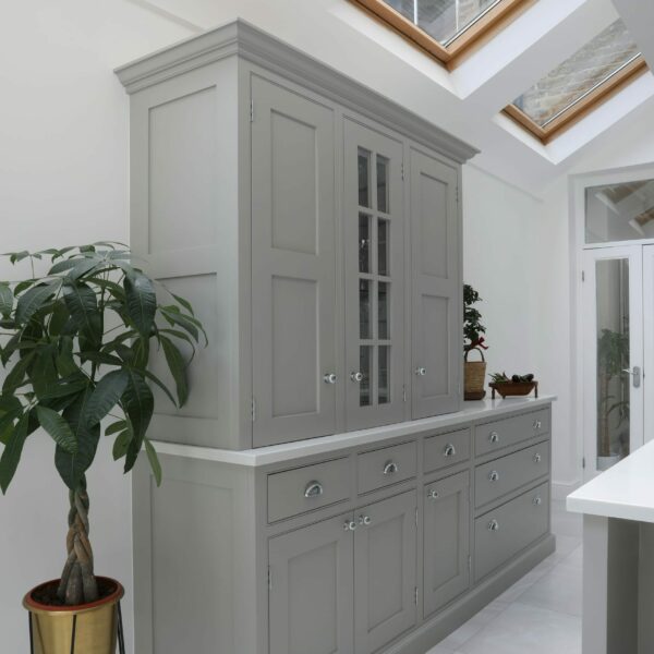 Clapham Painted Shaker Kitchen with dressers underneath skylights in side return extension. White floors and house plant next to kitchen cabinets