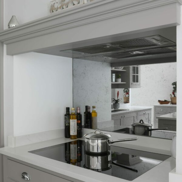 Clapham painted shaker kitchen with an induction hob built into a chimney, antique mirror splashback, integrated extractor, wide drawers under hob and silver cup handles
