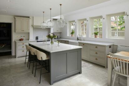East Sheen Shaker Kitchen with an island, a Belfast sink under a window with garden views, and a range cooker with a chimney surround.