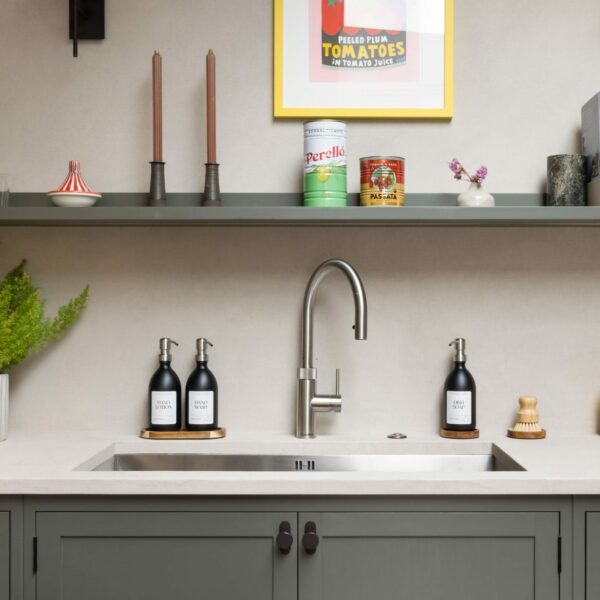Shaker kitchen with large stainless steel sink and a stainless steel Quooker boiling water tap, a floating shelf above with candles, ornaments and cook books.