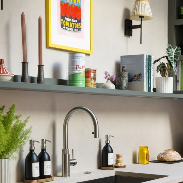 Shaker kitchen with large stainless steel sink and a stainless steel Quooker boiling water tap, a floating shelf above with candles, ornaments and cook books.
