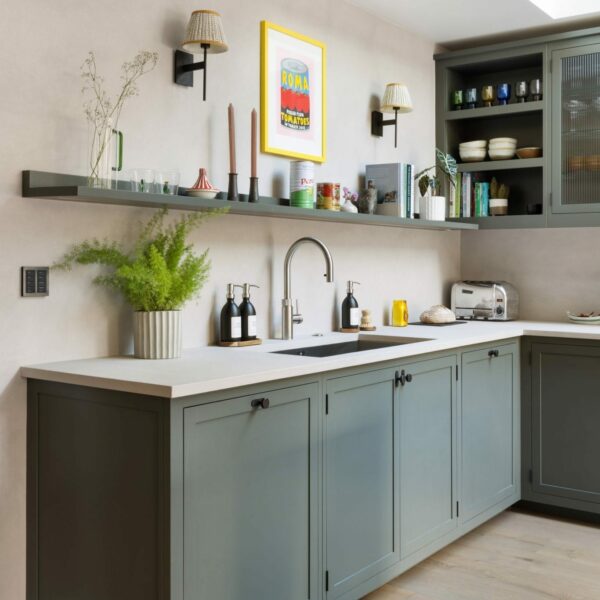 Shaker kitchen painted in dark grey-green, stainless steel sink, boiling water tap, and an open shelf showcasing ornaments and cook books.