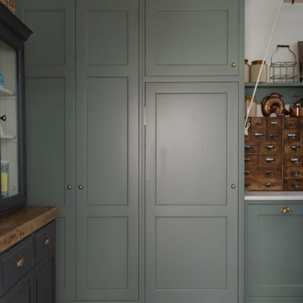 Muted green Shaker cabinets in a utility room with a black and white checkered floor.
