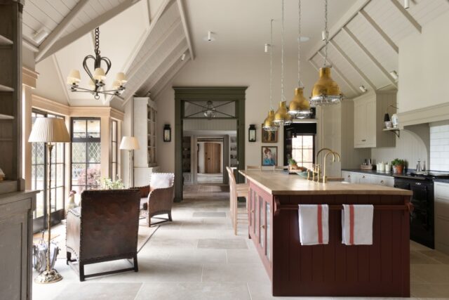 Spacious handmade kitchen with vaulted ceiling, red island, brass pendant lights and classic country-style detailing.