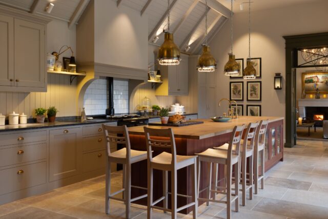 Bespoke handmade grey Shaker kitchen with plum painted island, vaulted ceiling and open fireplace in Surrey country home by Higham Furniture