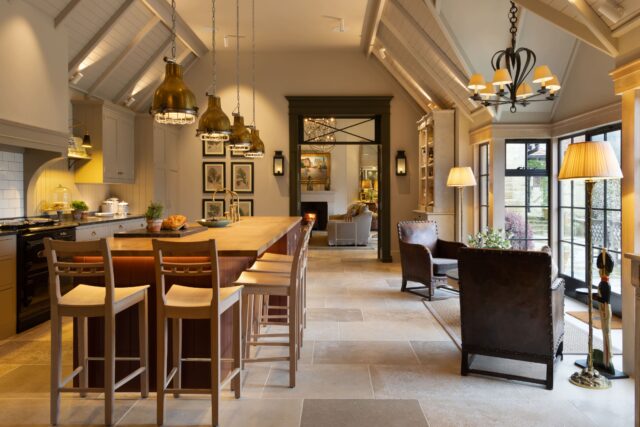 Bespoke open-plan handmade Shaker kitchen with vaulted ceiling, stone floor and view through to sitting room, Haslemere Surrey by Higham Furniture