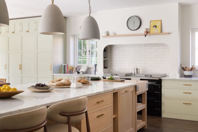 Bespoke shaker kitchen with sage green painted cabinets, natural oak island and arched Aga splashback by Higham Furniture