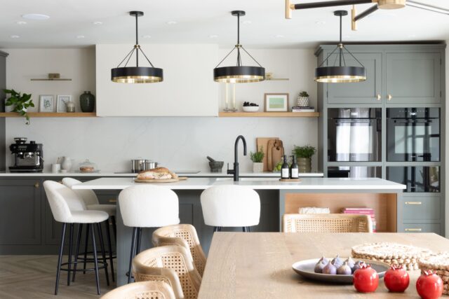 Modern bespoke kitchen with grey cabinetry, island seating and pendant lighting in open-plan dining space