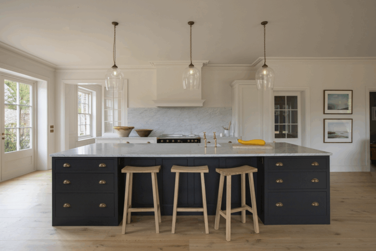 Large navy blue kitchen island with glass pendant lighting and oak bar stools, Higham
