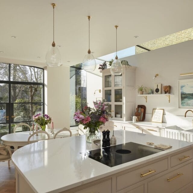 Herne Hill Painted Shaker Kitchen with a Bora downdraft hob on a curved island, Belfast sink in the background, dining table and crittal doors into the garden.