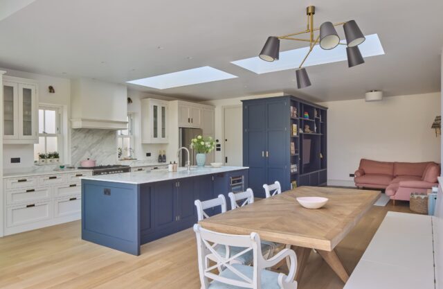 Bespoke handmade kitchen with navy blue island, white painted cabinets and skylights in open-plan family living space by Higham Furniture