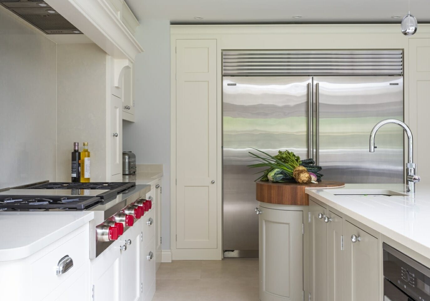 Rickmansworth painted shaker kitchen. Rickmansworth Painted Shaker Traditional Kitchen. Circular chopping board on island with Walnut end grain worktop. Subzero fridge and freezer. Island with Quooker tap. Wolf hob in custom chimney. Westin extractor.